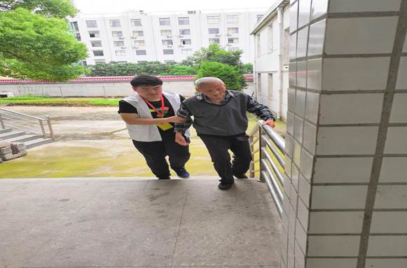 说明:志愿者梁亚东扶王三娃爷爷上楼梯